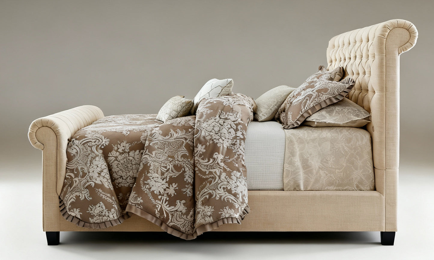 Beige upholstered bed with floral-patterned blanket and pillows on a neutral background