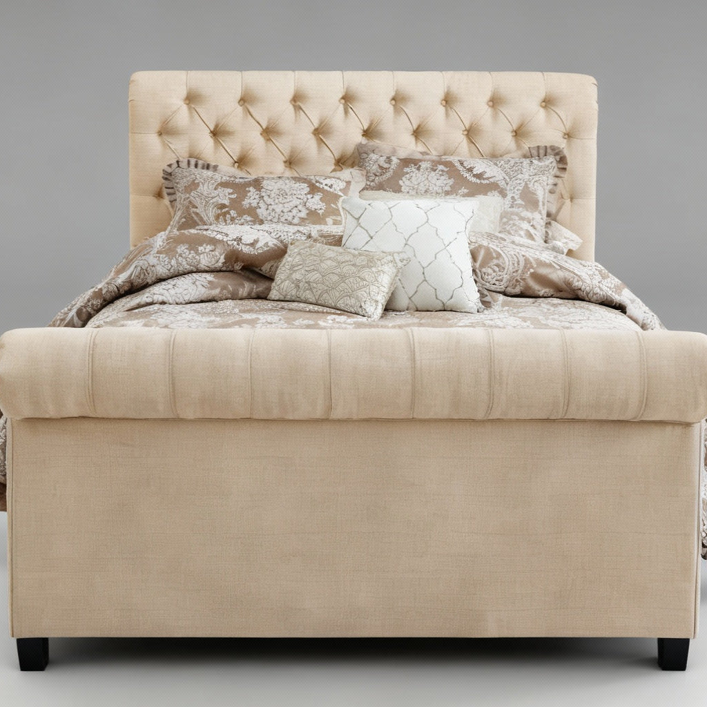 Beige upholstered ottoman with decorative pillows and a blanket on a gray background